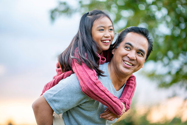 Man carrying young girl on back smiling