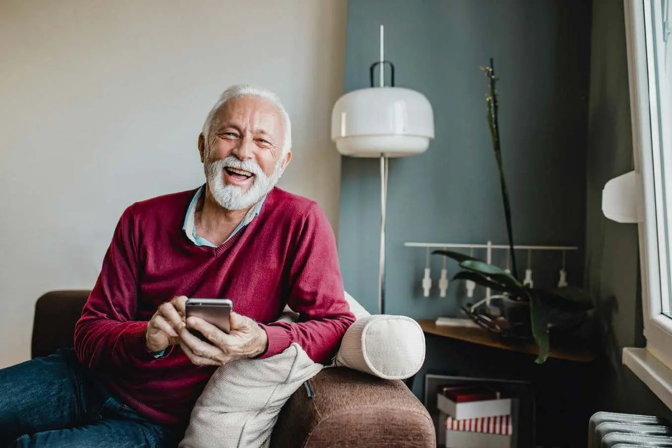 Man sitting on a sofa smiling with a mobile phone